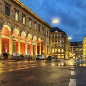 Das Wandbild Am Max-Joseph-Platz zeigt die nächtliche Oper in München mit stimmungsvoller Beleuchtung und Spiegelungen auf dem regennassen Asphalt.