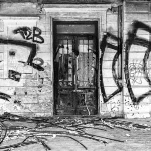 Schwarz-weiß Fotografie Czech Graffity zeigt eine verfallene Fassade mit ausdrucksstarken Graffiti und einer alten Holztür.