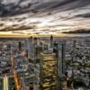 Das Panorama-Wandbild Frankfurter Abendspektakel zeigt die weitläufige, beleuchtete Skyline von Frankfurt am Main unter einem dramatischen Wolkenhimmel.