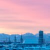 Das Panorama-Wandbild Frauenkirche am Morgen zeigt die Münchner Skyline mit Alpenpanorama unter einem rosa leuchtenden Winterhimmel.