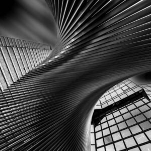 Die schwarz-weiß Fotografie From Underneath zeigt eine dynamisch geschwungene Treppenstruktur vor einer modernen Glasfassade in extremer Froschperspektive.