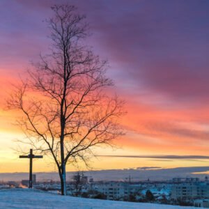 Das Wandbild Morgens vom Olympiaberg zeigt einen verschneiten Hügel mit markantem Baum und Gipfelkreuz vor einem farbenprächtigen Sonnenaufgang über München.