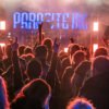 Das Wandbild Parasite Inc zeigt die jubelnde Menschenmenge mit „Pommesgabel“-Gesten vor der beleuchteten Bühne der Metal-Band im 3:2 Format.