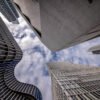 Das Wandbild Schau nach oben in Frankfurt zeigt eine beeindruckende Untersicht moderner Wolkenkratzer vor einem leicht bewölkten Himmel im 3:2 Format.