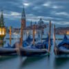 Das Wandbild Schlafende Gondeln zeigt blau abgedeckte Gondeln in Venedig vor der Basilika San Giorgio Maggiore in der blauen Stunde.