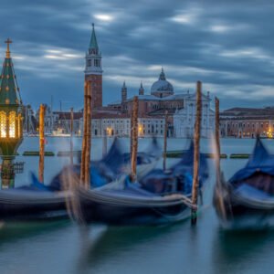Das Wandbild Schlafende Gondeln zeigt blau abgedeckte Gondeln in Venedig vor der Basilika San Giorgio Maggiore in der blauen Stunde.