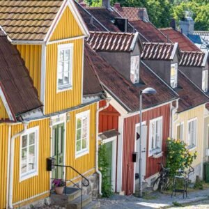 Das Wandbild Schwedisches Idyll zeigt eine Reihe farbenfroher, traditioneller Holzhäuser in einer gemütlichen schwedischen Gasse im 3:2 Format.