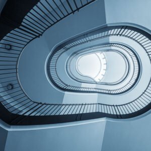 Das Wandbild Treppenhausgeometrie zeigt eine abstrakte Untersicht eines geschwungenen Treppenhauses in kühlen Blautönen im 3:2 Format.