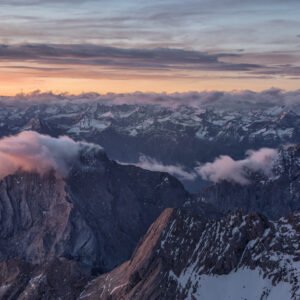 Fotokunst Wattewolken Zugspitze: Schroffe Berggipfel im Morgenlicht mit sanften, rosafarbenen Wolkenformationen im Vordergrund.