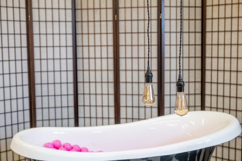 Kreatives Setup im Fotostudio Kaufbeuren: Eine freistehende Badewanne mit rosa Bällebad und Vintage-Leuchten vor einem Paravent.
