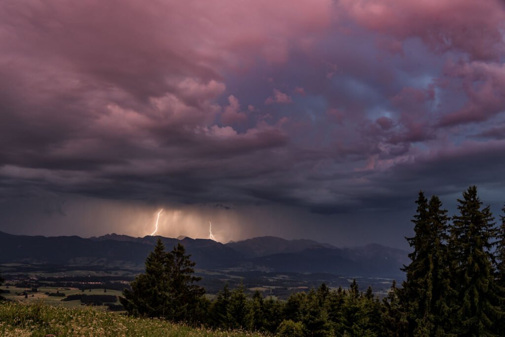 Spektakulärer Blitzeinschlag über den Alpen, fotografiert vom Auerberg bei dramatischer Abendstimmung.
