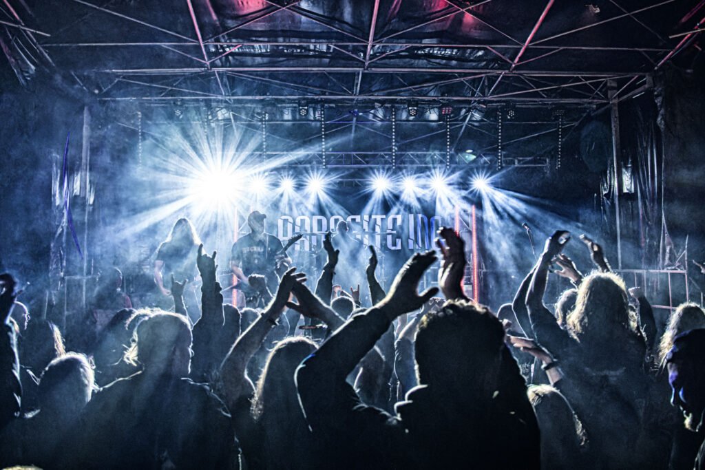 Dynamische Live-Aufnahme von Parasite Inc. auf einer hell beleuchteten Bühne mit jubelnder Crowd im Vordergrund.