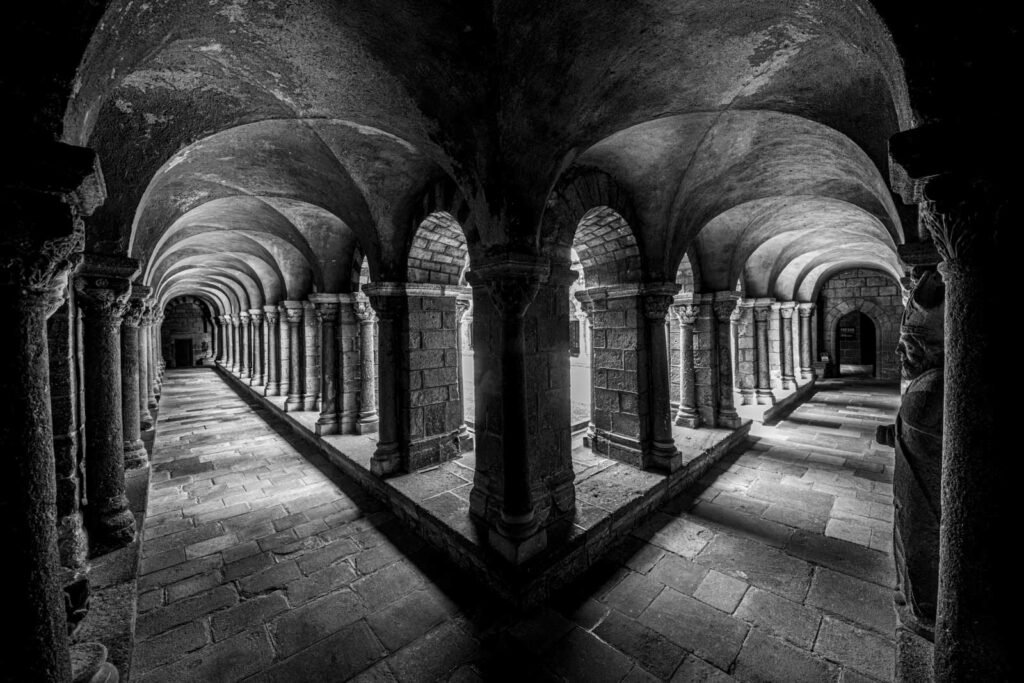 Historischer Kreuzgang einer Abtei in dramatischer schwarz-weiß Fotografie mit Fokus auf die Säulengänge.
