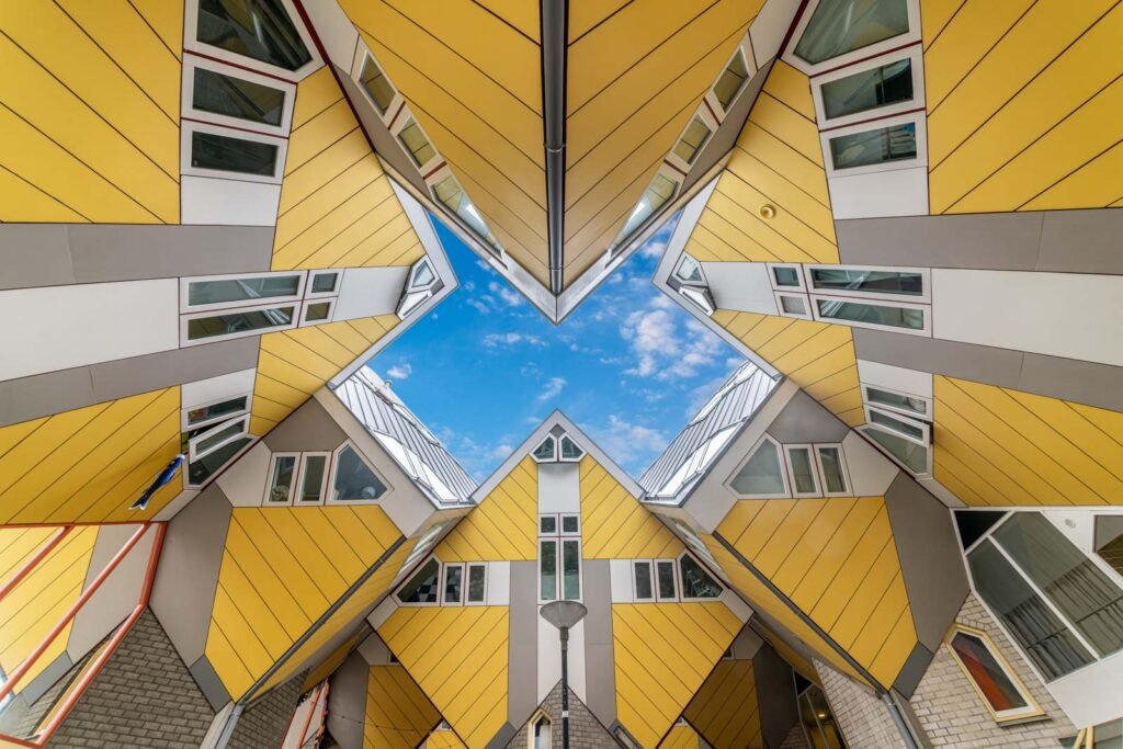 Symmetrische Froschperspektive der gelben Kubushäuser in Rotterdam mit Blick auf den blauen Himmel.