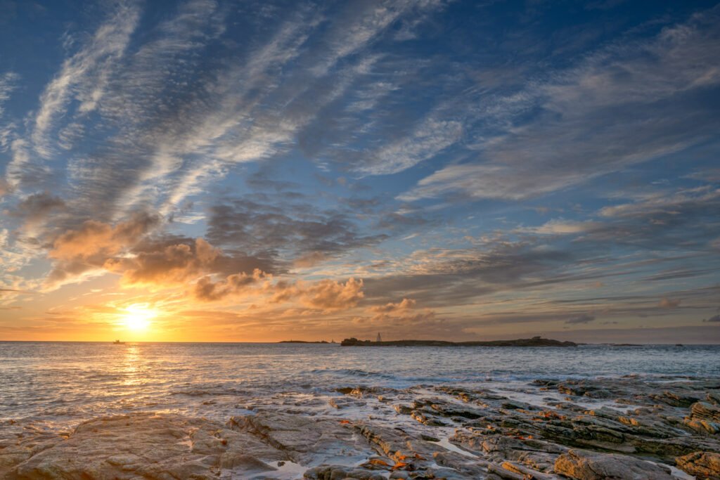 Felskante am Meer bei Sonnenaufgang mit aufstrebenden Wolken – Landschaftsfotografie von Roland Seichter