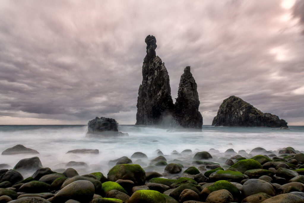 Dramatische Küstenlandschaft auf Madeira mit markanten Felsformationen im brausenden Meer unter bewölktem Himmel.