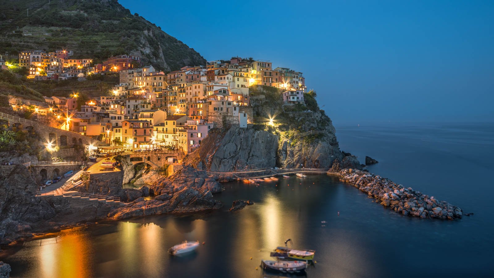 Das beleuchtete Dorf Manarola in Cinque Terre zur blauen Stunde am Meer.