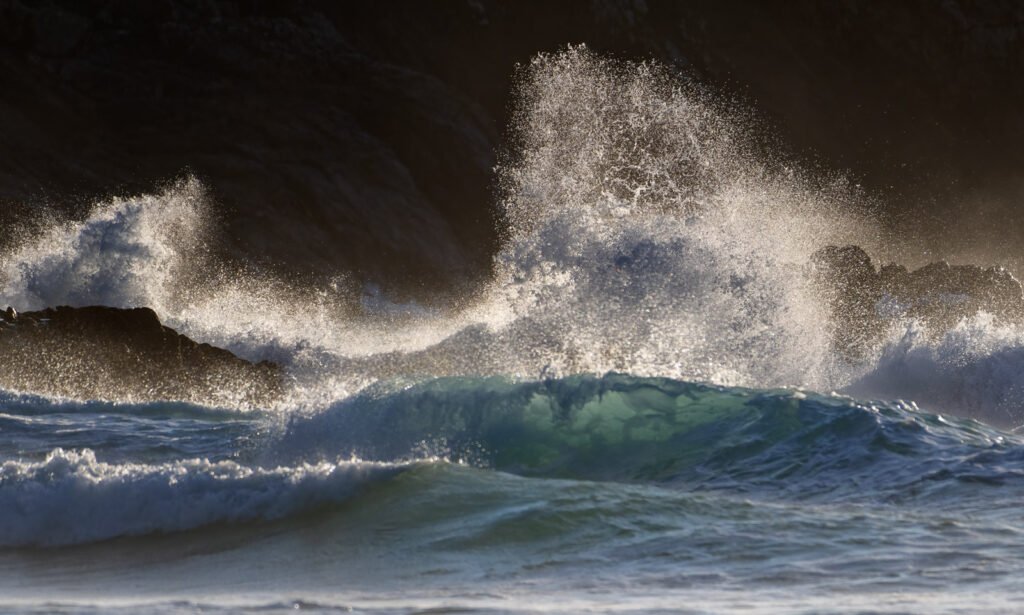 Detail der Meereswelle im Gegenlicht: Dynamische Landschaftsfotografie mit spritzender Gischt.