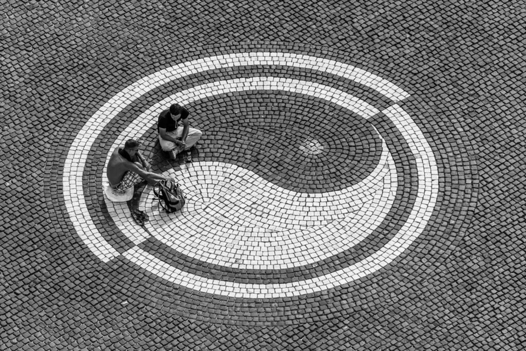 Zwei Personen auf einer gepflasterten Fläche mit Yin-Yang-Muster.