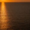 Minimalistische Fotografie Orange Water mit goldenen Sonnenreflexionen auf der Meeresoberfläche