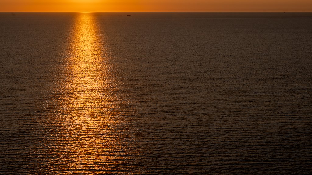 Minimalistische Fotografie Orange Water mit goldenen Sonnenreflexionen auf der Meeresoberfläche