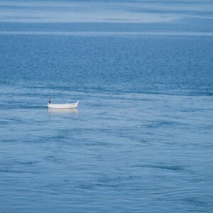 Minimalistische Fotografie Weißes Boot auf einer ruhig strukturierten blauen Meeresoberfläche