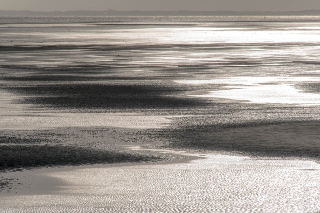 Reduzierte Atmosphäre von Wasser am Strand im Gegenlicht – minimalistisches Wandbild für Ruhe und Fokus.