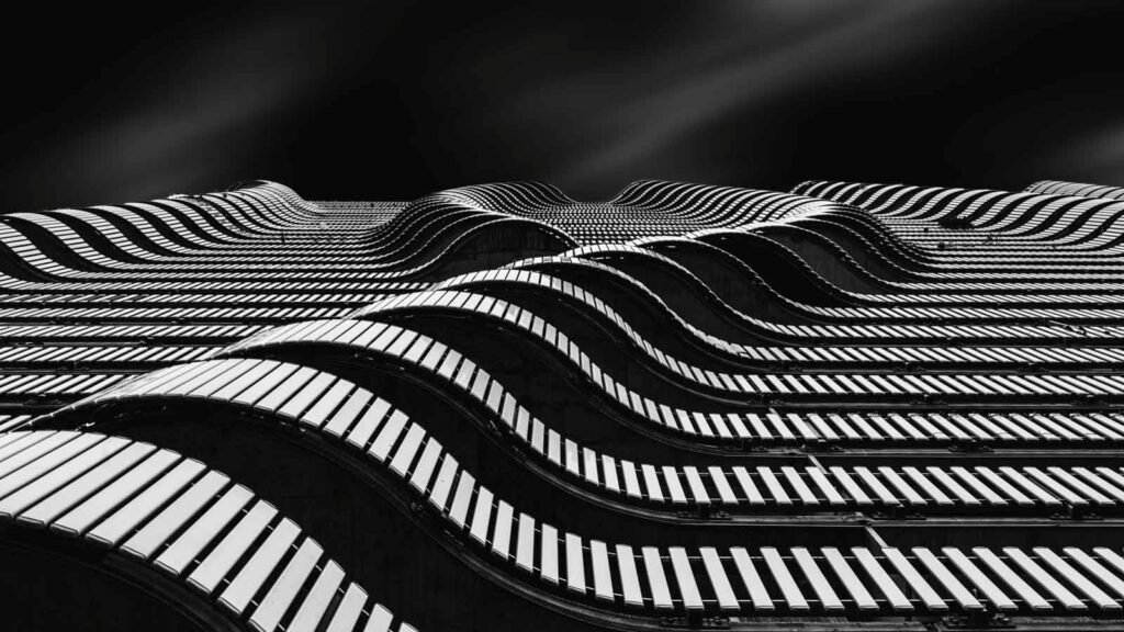 Abstraktes Schwarz-Weiß-Foto geschwungener Balkone einer modernen Fassade in Wellenoptik.