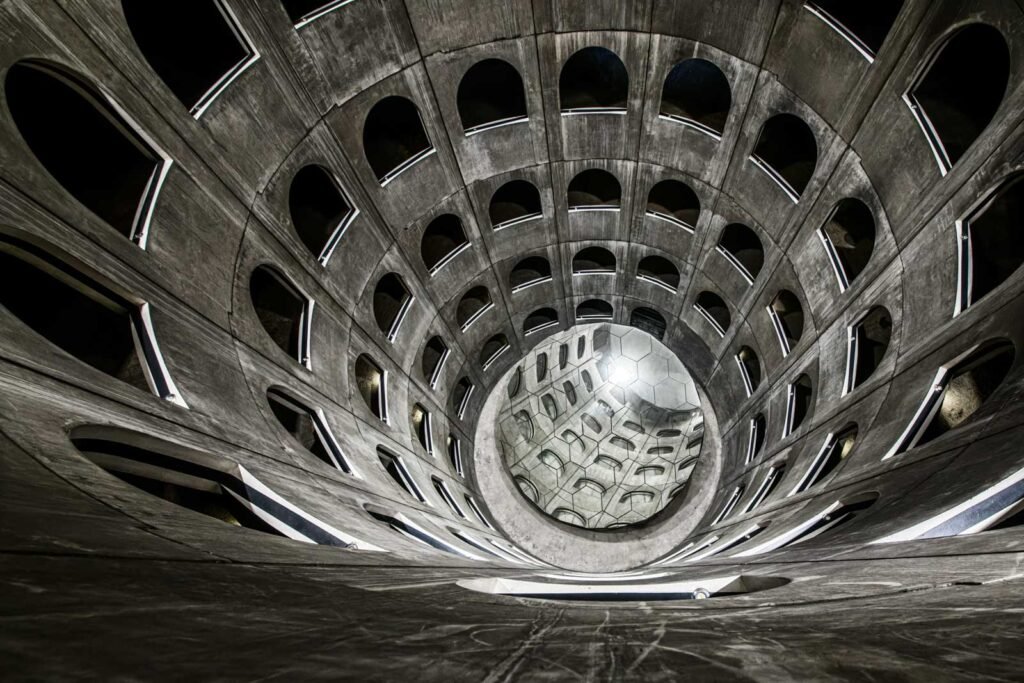 Blick von oben in ein modernes Gebäude aus Beton mit kreisförmig angeordneten Fensteröffnungen.