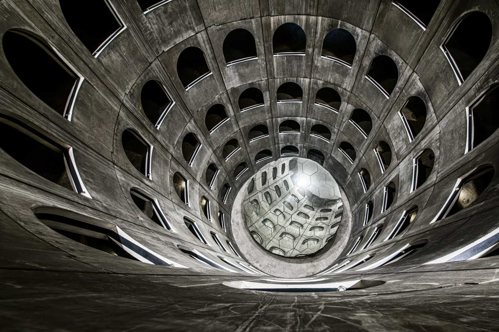 Blick von oben in ein modernes Gebäude aus Beton mit kreisförmig angeordneten Fensteröffnungen.