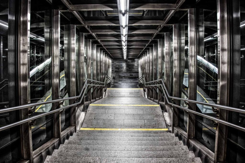 Symmetrischer Blick nach unten in einen modernen Treppenaufgang aus Glas und Stahl.