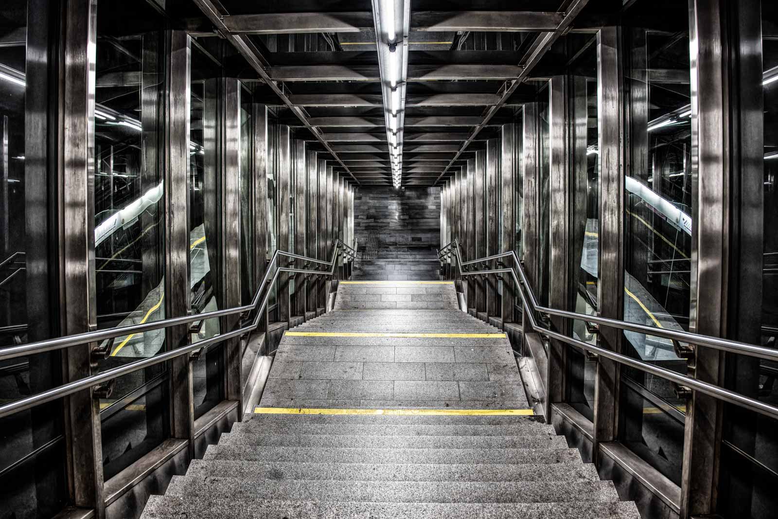 Symmetrischer Blick nach unten in einen modernen Treppenaufgang aus Glas und Stahl.