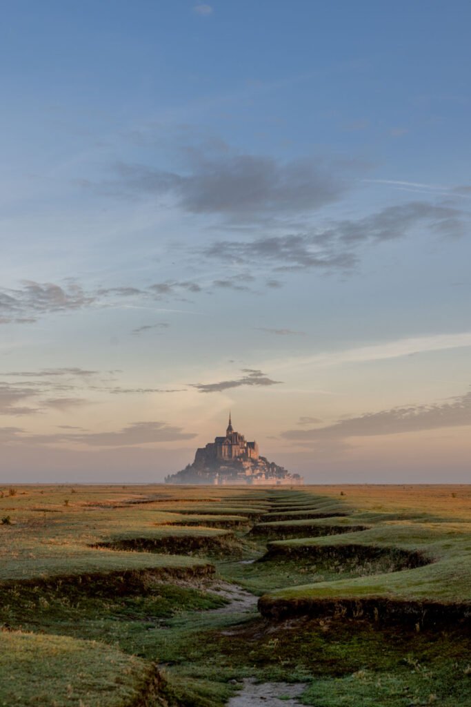Die Inselburg Mont Saint-Michel in der Normandie bei sanftem Morgenlicht über der weiten Landschaft.