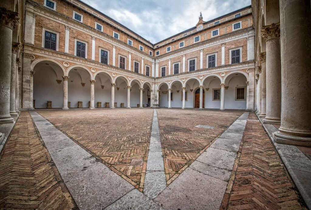 Symmetrische Innenhofansicht des Palazzo Ducale in Urbino mit prachtvollen Arkaden.