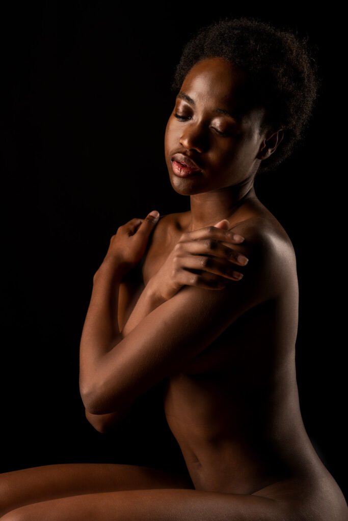 Ästhetisches Porträt einer schwarzen Frau vor dunklem Hintergrund in sanftem Licht.