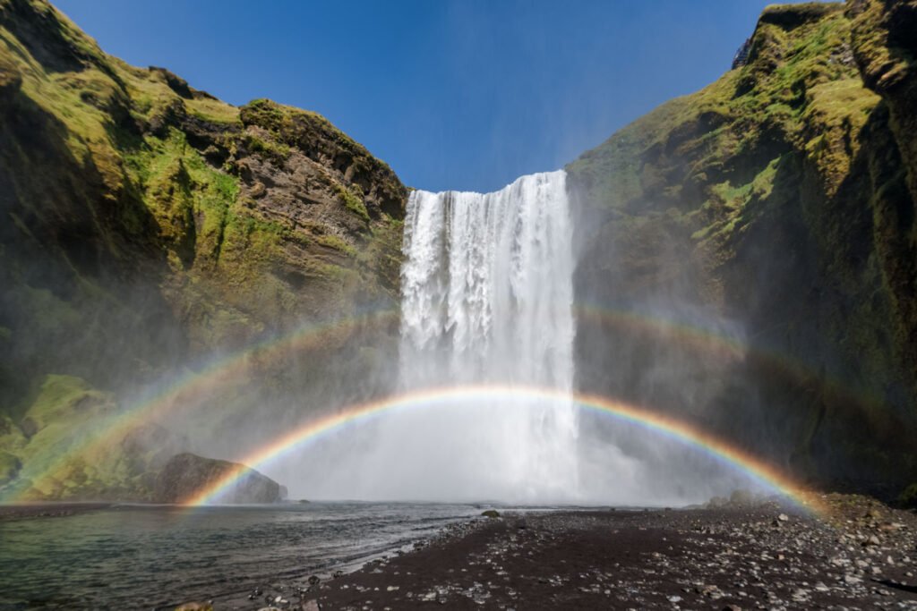 Der Skógafoss Wasserfall in Island mit einem leuchtenden doppelten Regenbogen.
