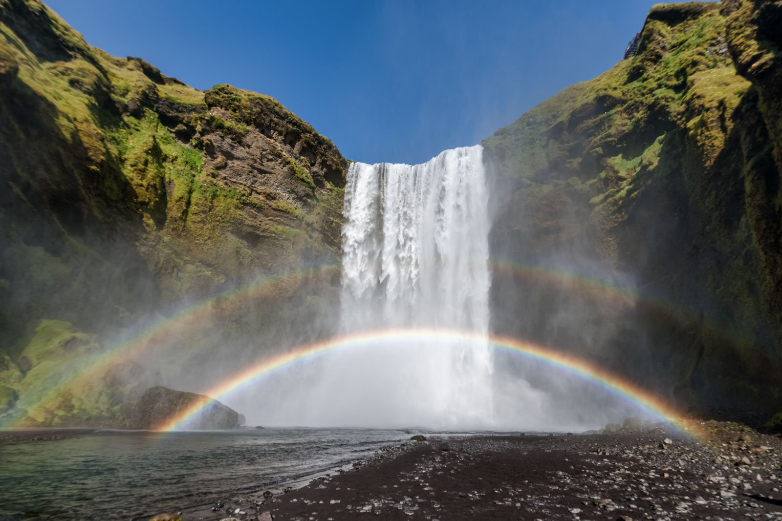 Der Skógafoss Wasserfall in Island mit einem leuchtenden doppelten Regenbogen.