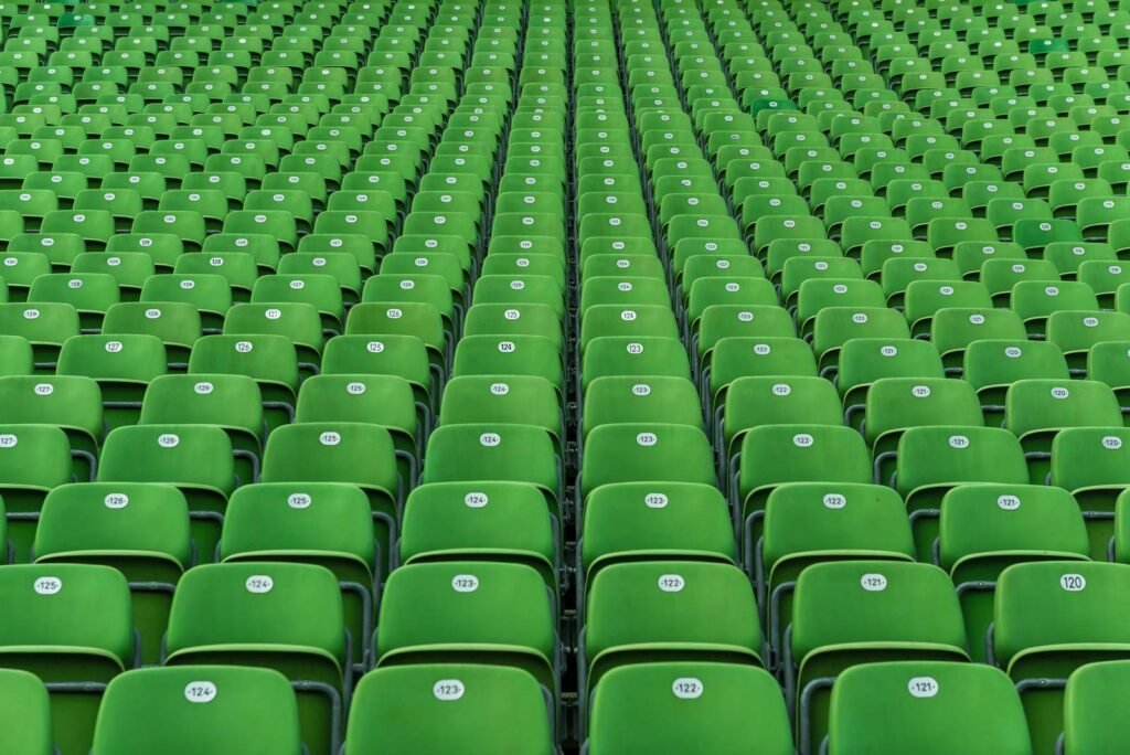 Abstraktes Muster aus unzähligen grünen Klappsitzen in einem großen Sportstadion.