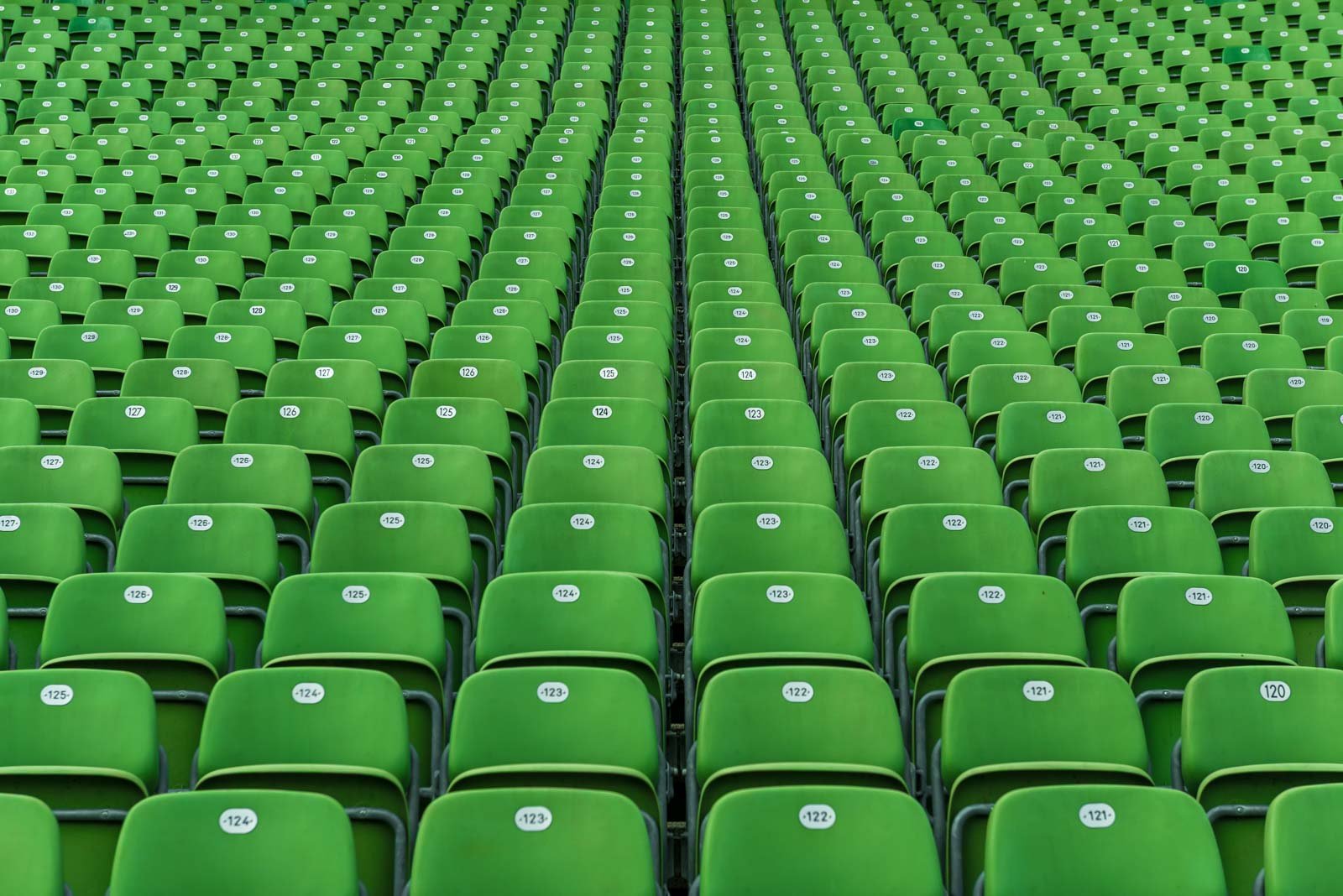 Abstraktes Muster aus unzähligen grünen Klappsitzen in einem großen Sportstadion.