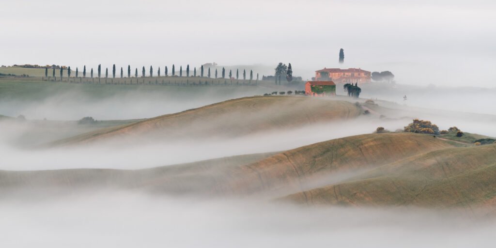 Blick auf das Anwesen Il Rigo in der Toskana, umgeben von dichten Nebelbänken am Morgen.