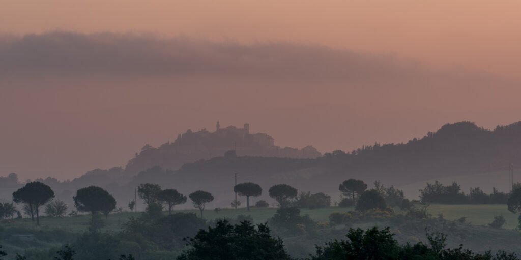 Die Silhouette einer thronenden Stadt auf einem Hügel in der Toskana während der Morgendämmerung.