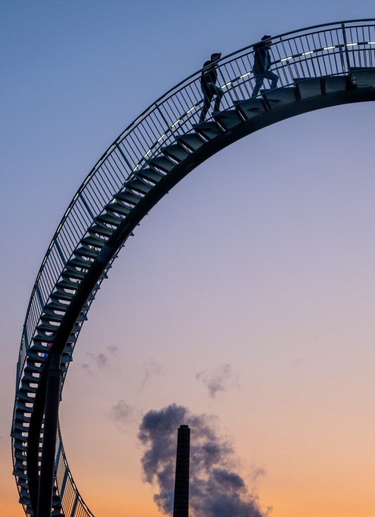 Silhouette einer geschwungenen Stahltreppe gegen einen Abendhimmel in Pastelltönen.
