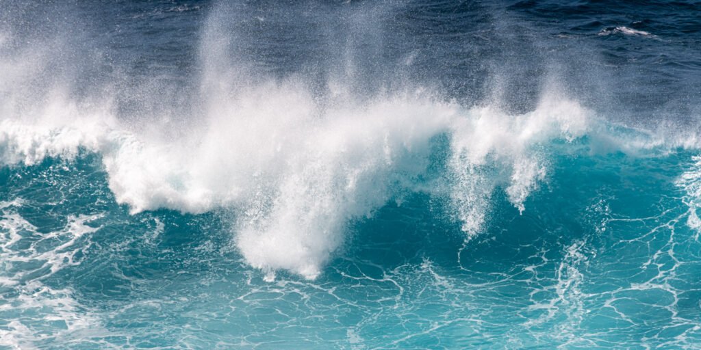 Dynamische Meeres-Landschaftsfotografie: Türkise Welle und weiße Gischt in Nahaufnahme.