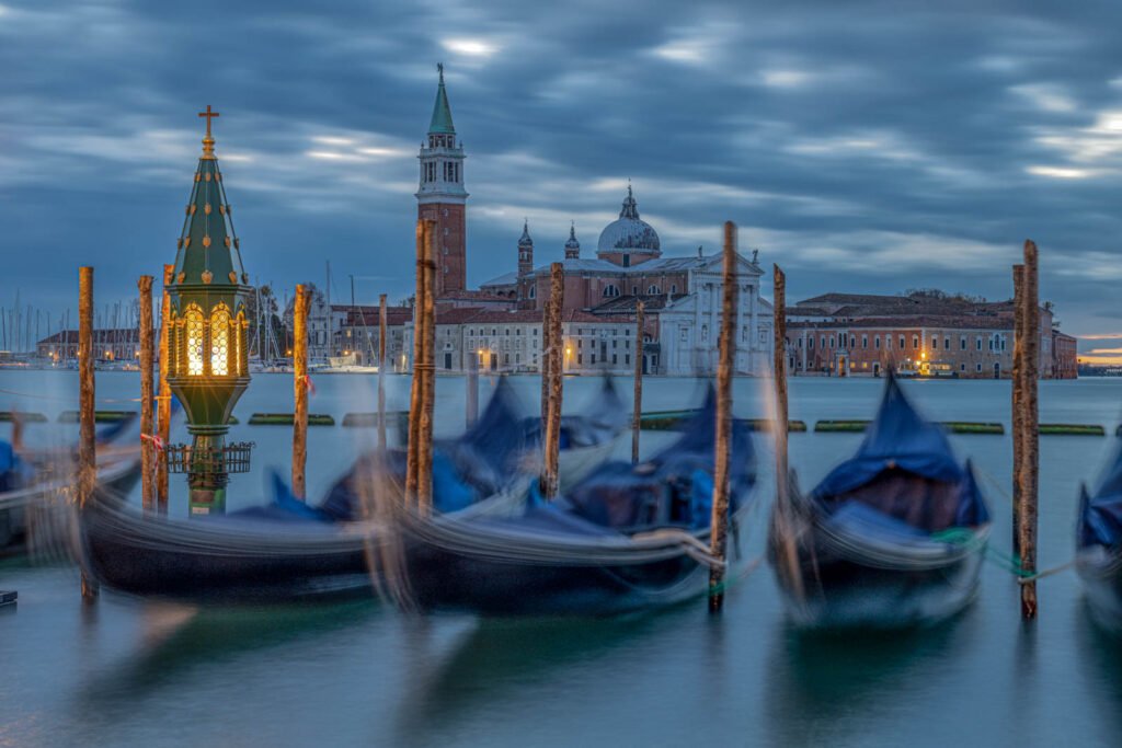 Sanft schaukelnde Gondeln in Venedig bei einer Langzeitbelichtung zur blauen Stunde mit Blick auf San Giorgio Maggiore.