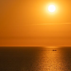 Wandbild "In the Evening": Ein Schiff auf dem Meer vor einem goldenen Sonnenuntergang.