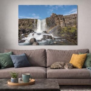 Öxarárfoss im Regenbogen Das Wandbild Öxarárfoss als farbenfrohes und belebendes Kunstwerk über einer Couch in einem hellen Wohnzimmer