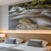 Das Wandbild Riesloch Wasserfall als natürlicher und beruhigender Akzent in einem stilvoll eingerichteten Hotelzimmer