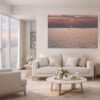 Das Wandbild Sonnenuntergang am See im 3:2 Format als stimmungsvoller und maritimer Blickfang über einer Couch im Wohnzimmer.