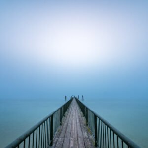 Wandbild "To the Light": Ein langer Steg, der im dichten Nebel über dem Wasser verschwindet.