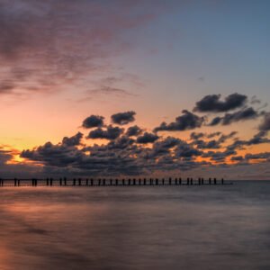 Das Wandbild Abend in Zingst zeigt einen stimmungsvollen Sonnenuntergang an der Ostsee mit Buhnen im Format 16:9.